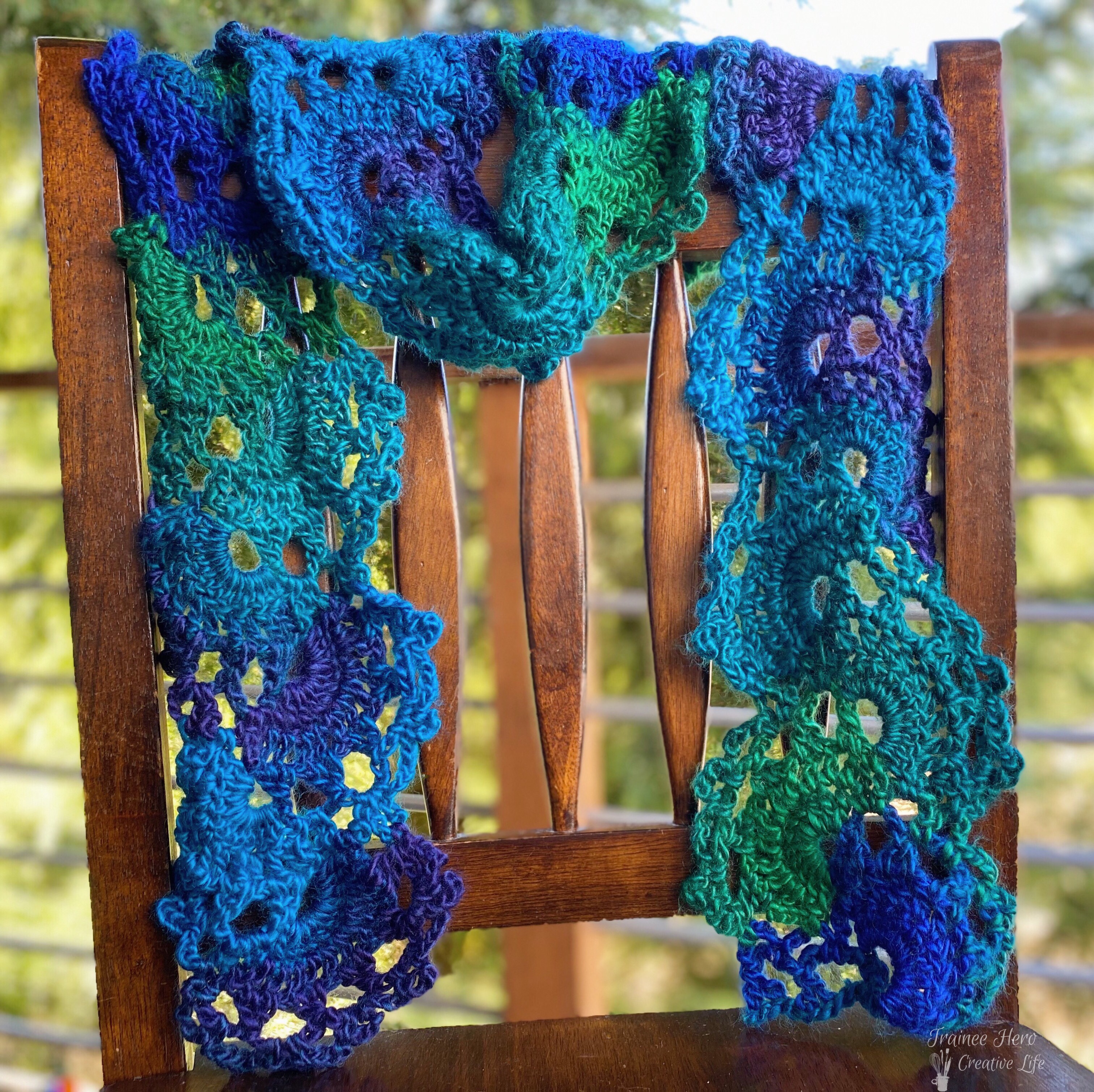Zinnia Scarf, a crochet edging pattern scarf, draped over a chair.
